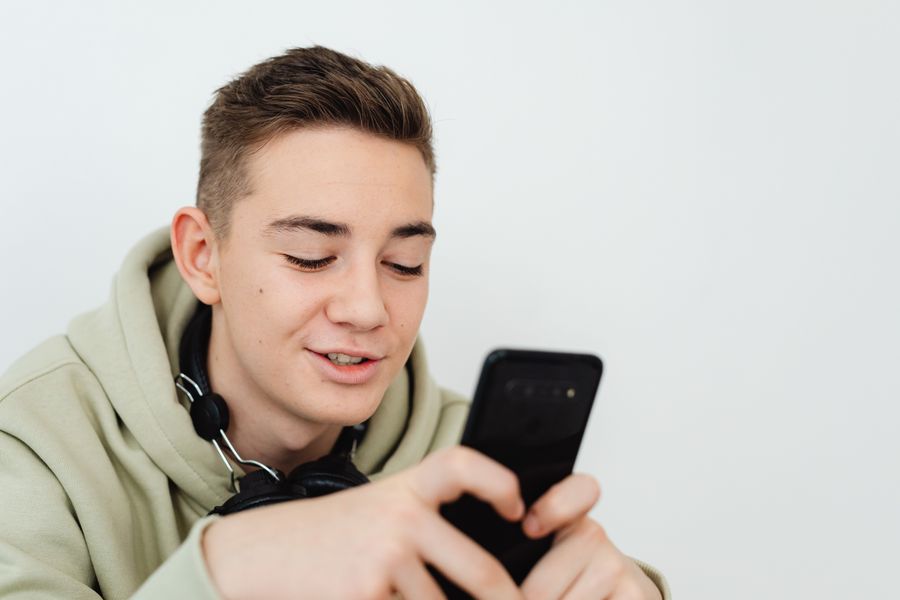 Adolescente sorrindo enquanto usa o celular