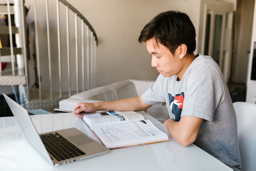 Aluno fazendo a tarefa com notebook e livro